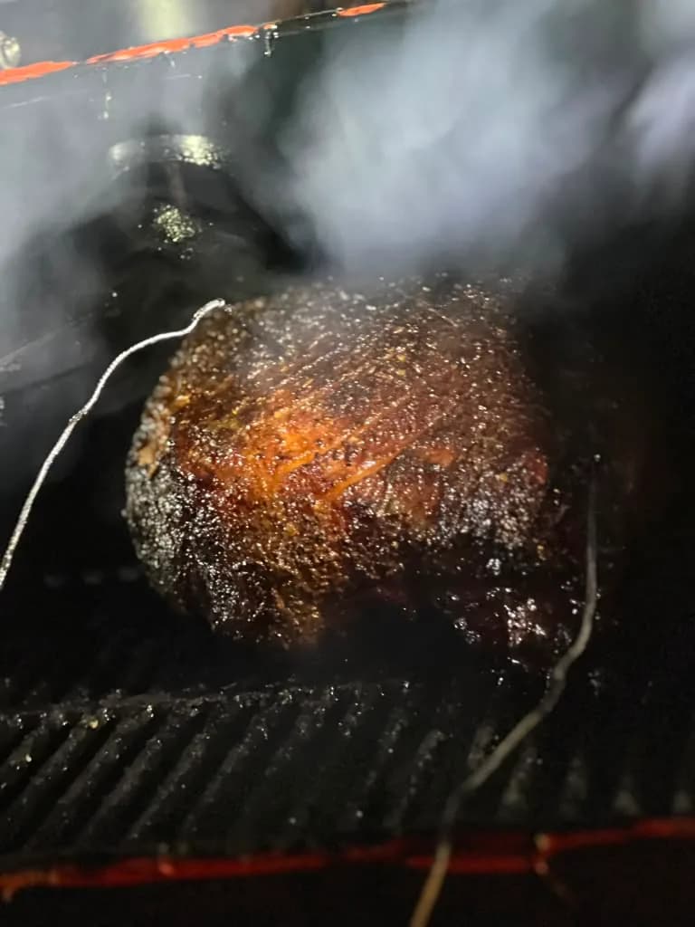 A charred steak cooking over a smoking grill